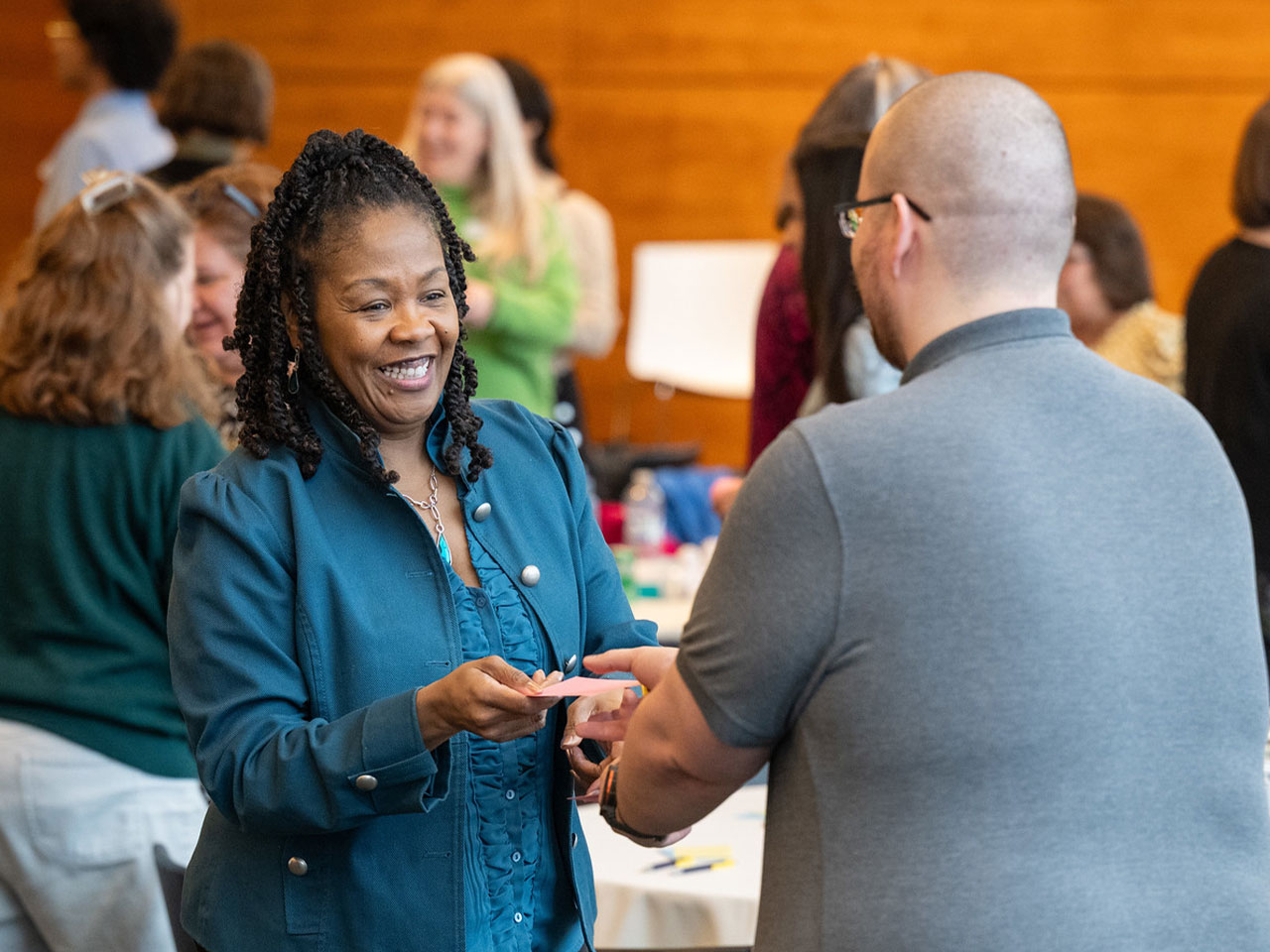 At an event at Ross, two participants greet each other and exchange cards during a group activity