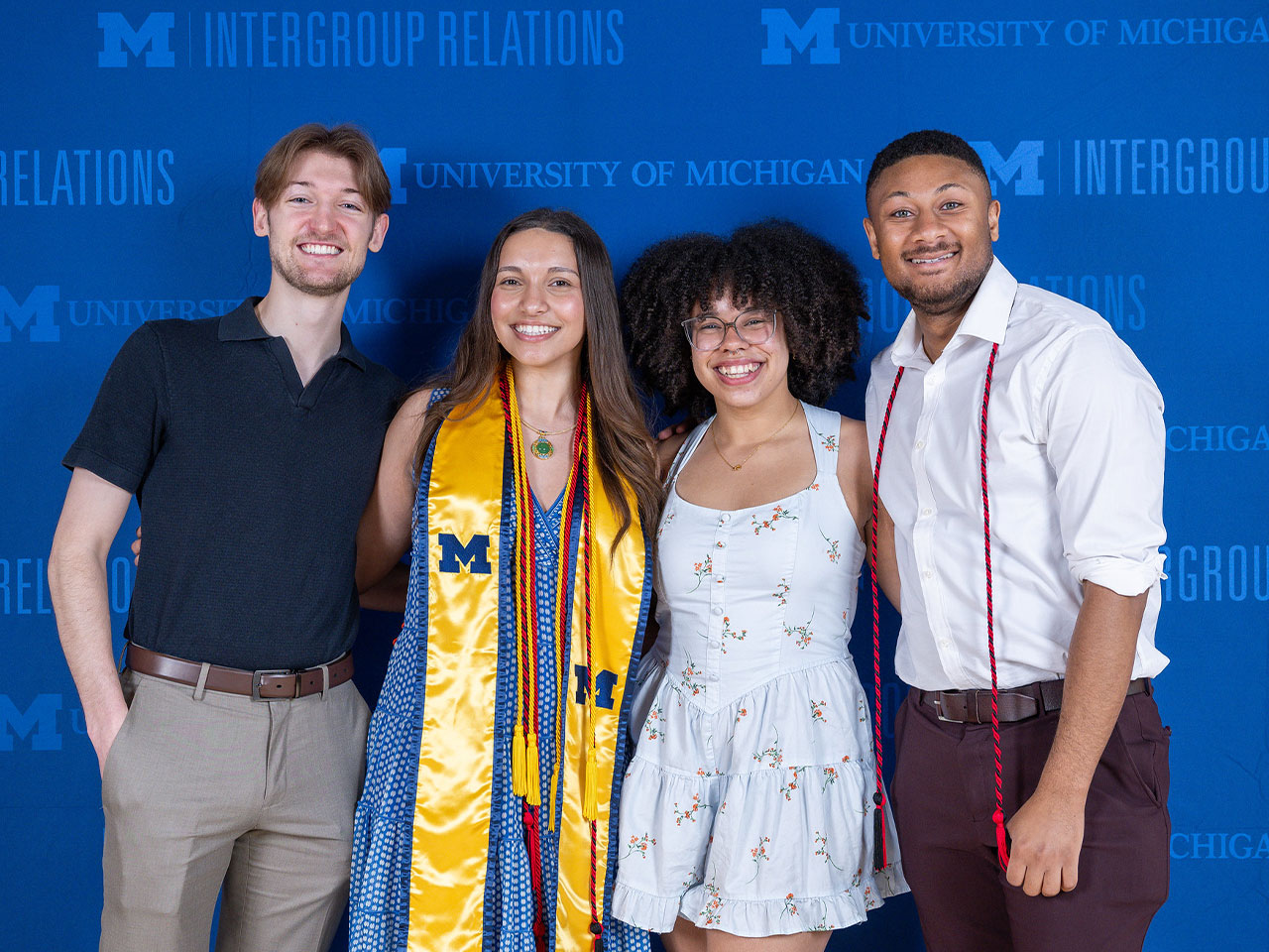 Four IGR graduates in front of IGR logo step-and-repeat banner at the annual award ceremony