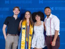 Small group of IGR graduates standing in front of the branded step-and-repeat banner