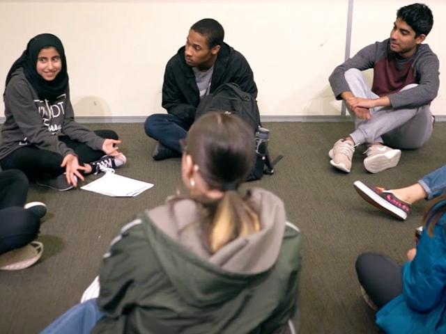 ALA 122 students having a dialogue, seated on the floor in a circle