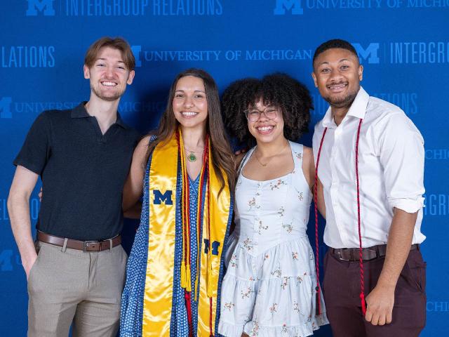 4 IGR students in front of the step-and-repeat banner
