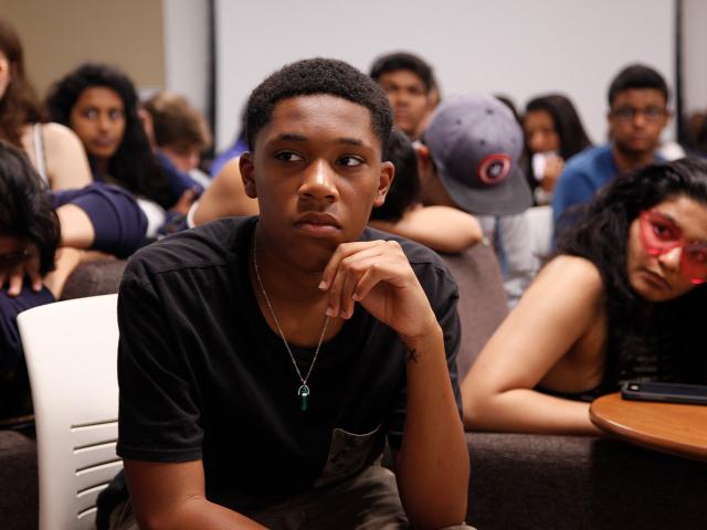 Close-up photo of a student participant among peers seated in a classroom