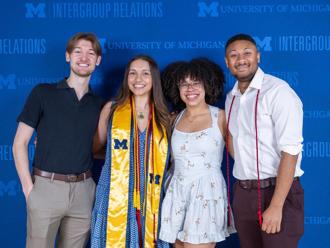 Small group of IGR graduates standing in front of the branded step-and-repeat banner