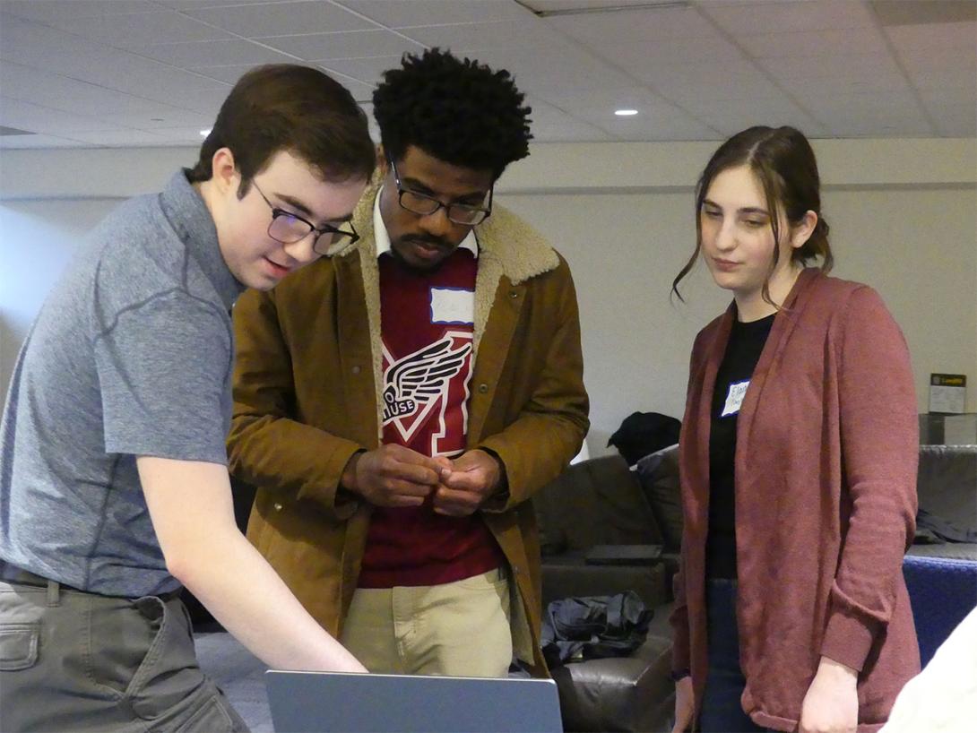 Three students referring to on-screen information as they discuss a classroom activity